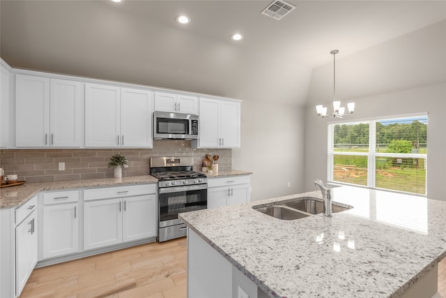 kitchen with lofted ceiling, stainless steel appliances, white cabinetry, tasteful backsplash, and sink