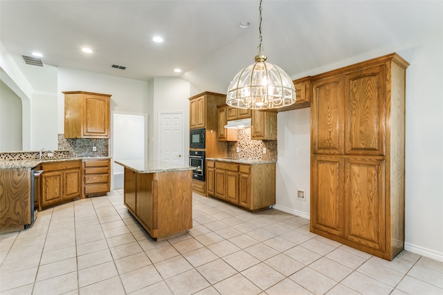 kitchen featuring black appliances, light stone countertops, a center island, and backsplash