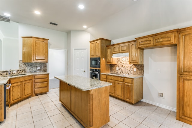 kitchen with a kitchen island, backsplash, sink, black appliances, and light stone counters