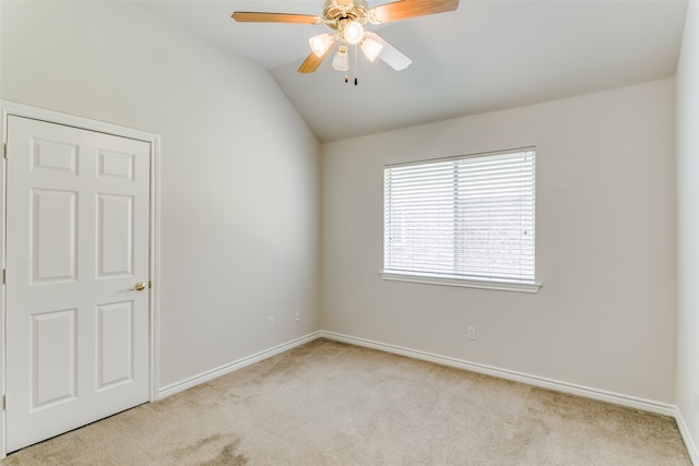 carpeted spare room with ceiling fan and vaulted ceiling