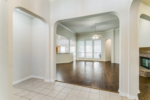 interior space featuring crown molding, a brick fireplace, and light hardwood / wood-style floors