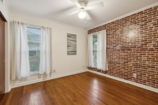 spare room with brick wall, ceiling fan, a healthy amount of sunlight, and wood-type flooring