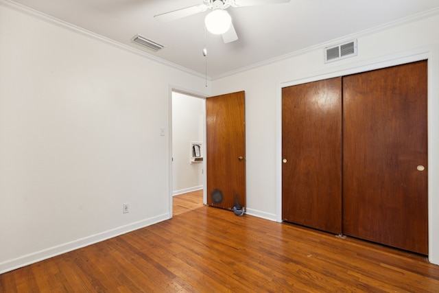 unfurnished bedroom with ceiling fan, a closet, ornamental molding, and wood-type flooring