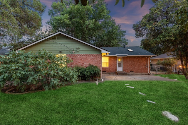 back house at dusk featuring a lawn