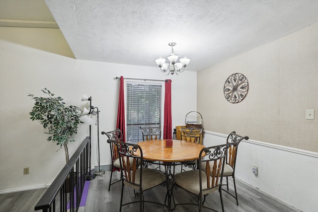 dining area featuring dark hardwood / wood-style flooring, a textured ceiling, and an inviting chandelier