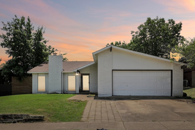 ranch-style home featuring central AC, a yard, and a garage