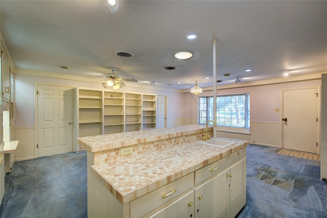 kitchen featuring ceiling fan, sink, dark carpet, a kitchen island, and tile countertops