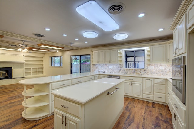 kitchen featuring crown molding, stainless steel appliances, a fireplace, and dark hardwood / wood-style floors