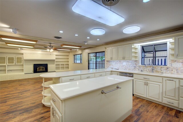 kitchen featuring dark hardwood / wood-style flooring, ornamental molding, a brick fireplace, ceiling fan, and sink