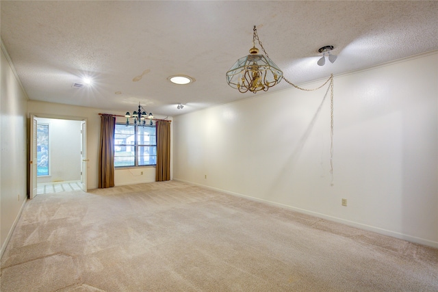 spare room featuring a textured ceiling, light colored carpet, and an inviting chandelier