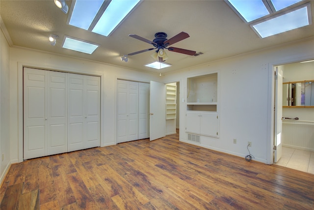 unfurnished bedroom featuring a textured ceiling, ceiling fan, tile patterned floors, ensuite bathroom, and two closets