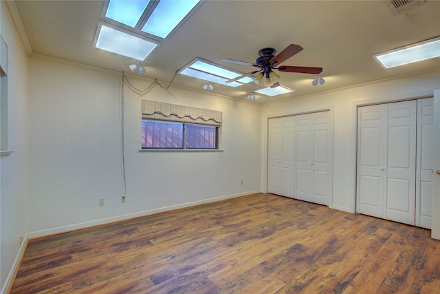 bedroom featuring ceiling fan, two closets, hardwood / wood-style flooring, and crown molding