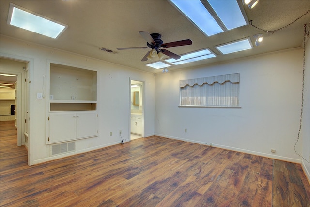 empty room with baseboards, ceiling fan, visible vents, and dark wood-style flooring