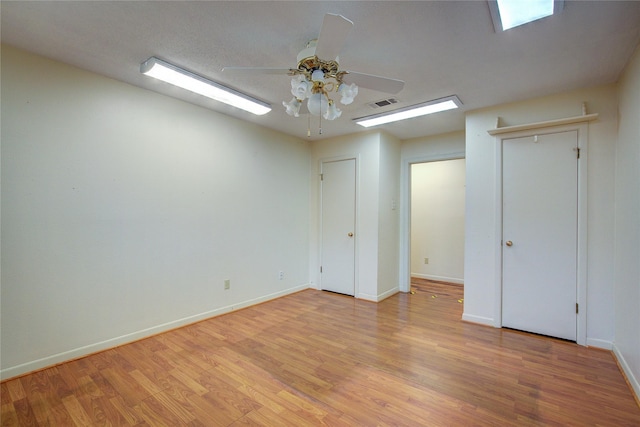 spare room with light wood-style floors, baseboards, visible vents, and ceiling fan