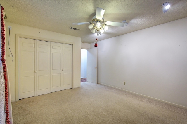 unfurnished bedroom with a textured ceiling, visible vents, a closet, and light colored carpet