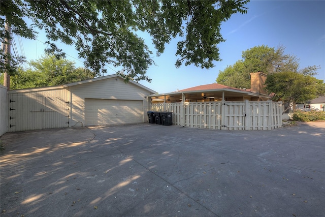 exterior space featuring a garage, an outbuilding, and fence