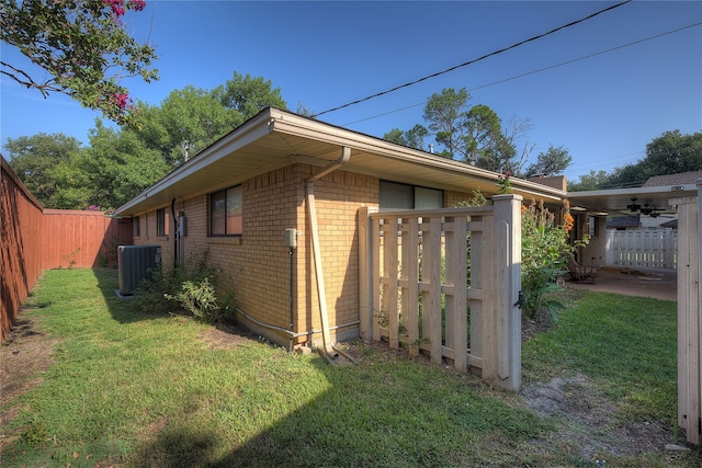 view of side of home featuring central air condition unit, ceiling fan, and a lawn