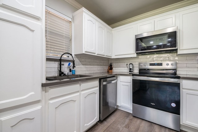 kitchen with hardwood / wood-style floors, sink, stainless steel appliances, and white cabinetry