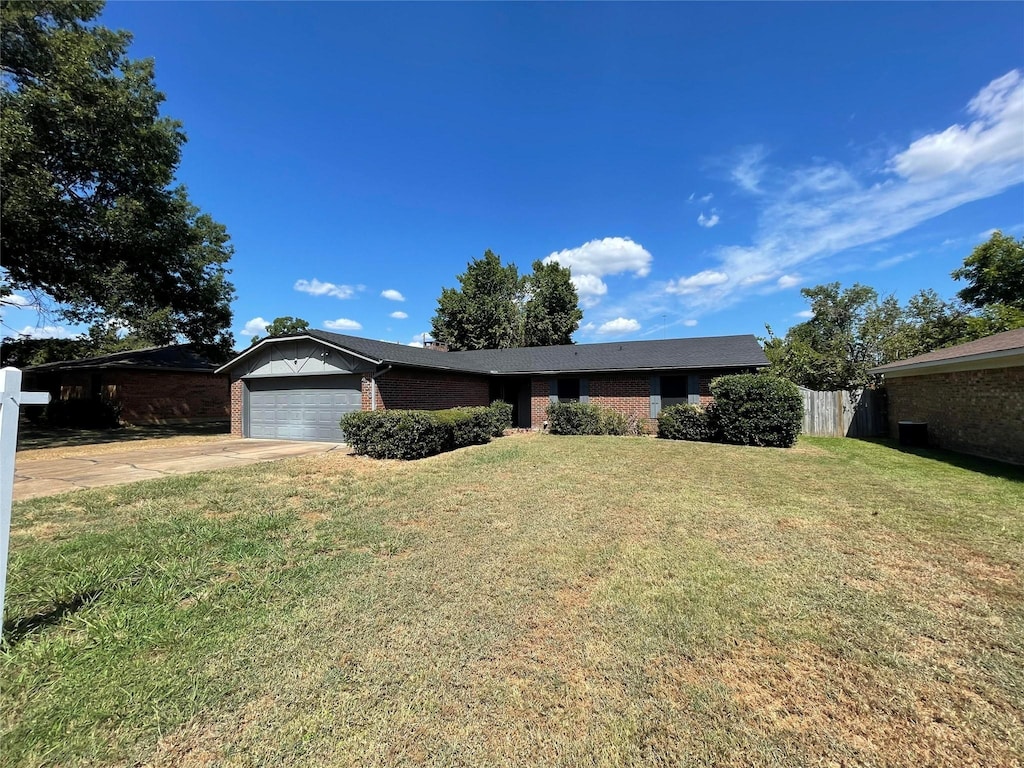 ranch-style house featuring an attached garage, a front lawn, concrete driveway, and brick siding