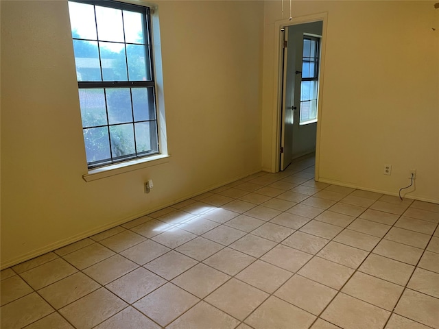 spare room with a wealth of natural light and light tile patterned flooring