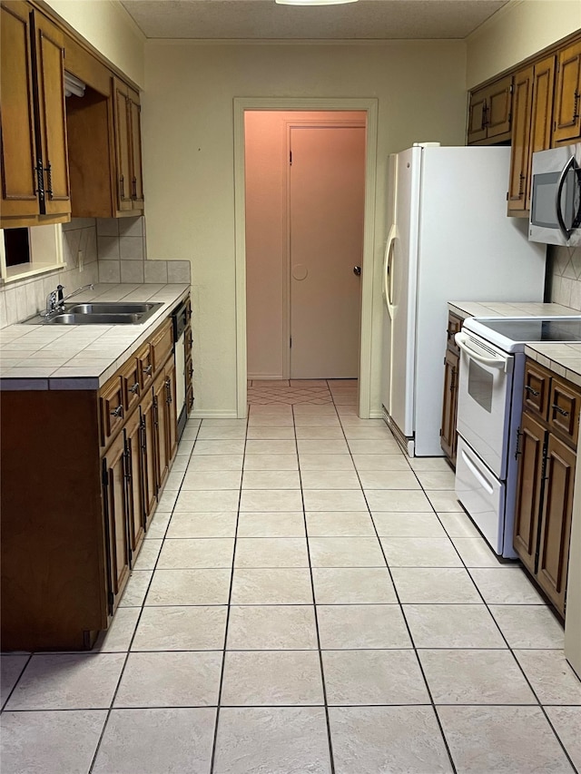 kitchen featuring tasteful backsplash, light tile patterned floors, tile countertops, sink, and white appliances