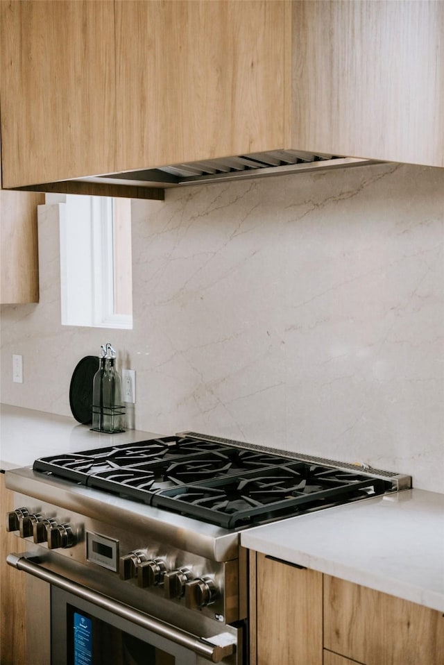 kitchen featuring decorative backsplash and high end stove