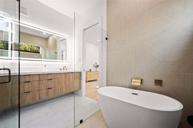 bathroom with vanity, plus walk in shower, and tile walls