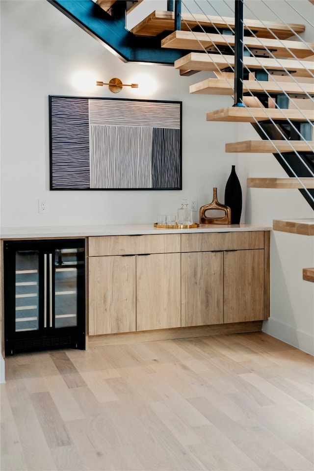 bar featuring wine cooler, light brown cabinetry, and light hardwood / wood-style floors