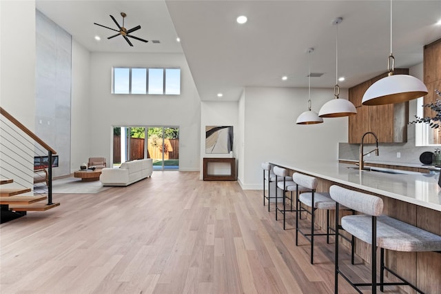 kitchen with pendant lighting, sink, a kitchen bar, decorative backsplash, and light hardwood / wood-style floors