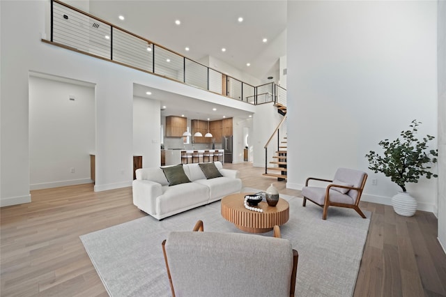 living room with a towering ceiling and light hardwood / wood-style flooring