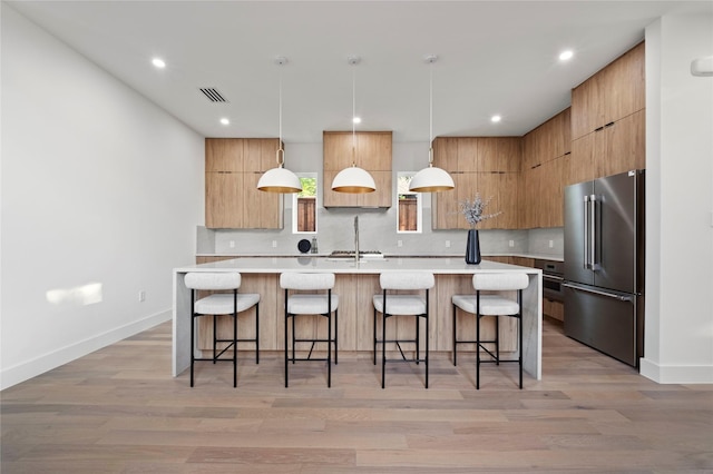 kitchen featuring a breakfast bar area, a large island, high end refrigerator, and decorative light fixtures