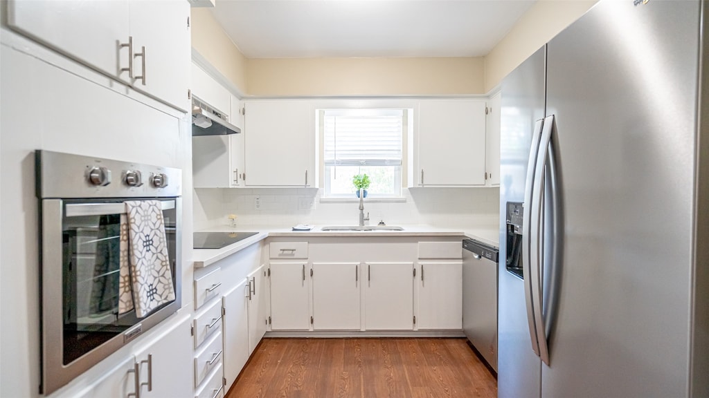 kitchen with stainless steel appliances, dark hardwood / wood-style floors, backsplash, extractor fan, and white cabinets