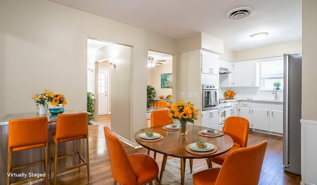 dining area with ceiling fan, dark wood-type flooring, and sink