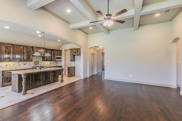 kitchen with hanging light fixtures, an island with sink, a breakfast bar, wood-type flooring, and ceiling fan