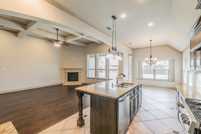 kitchen with an island with sink, ceiling fan with notable chandelier, sink, and a healthy amount of sunlight