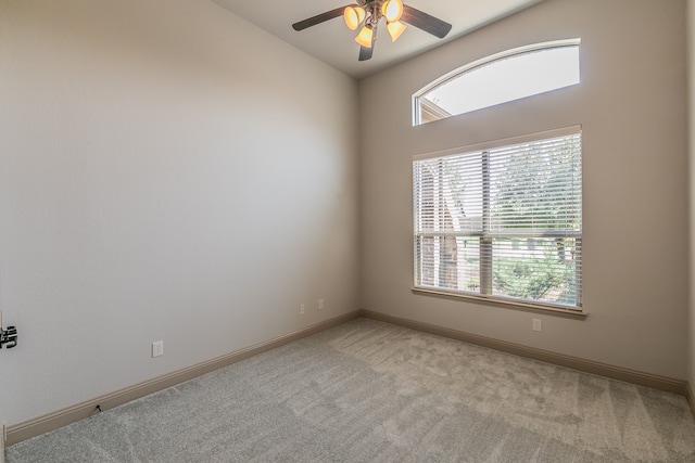 empty room featuring ceiling fan, light carpet, and vaulted ceiling