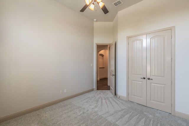 unfurnished bedroom with ceiling fan, light colored carpet, and a closet