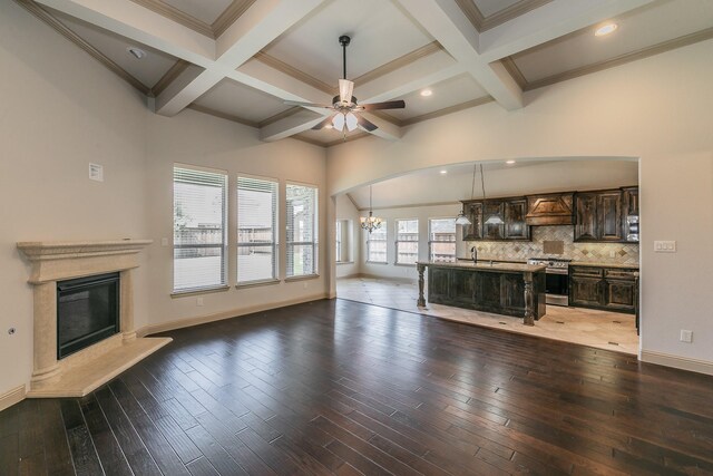 unfurnished living room with coffered ceiling, sink, ceiling fan with notable chandelier, and hardwood / wood-style floors