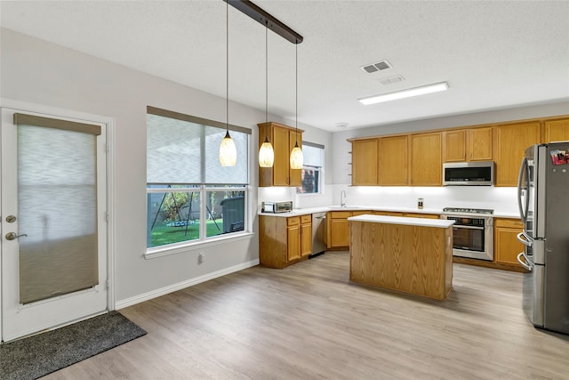 kitchen featuring light hardwood / wood-style flooring, hanging light fixtures, a center island, stainless steel appliances, and sink