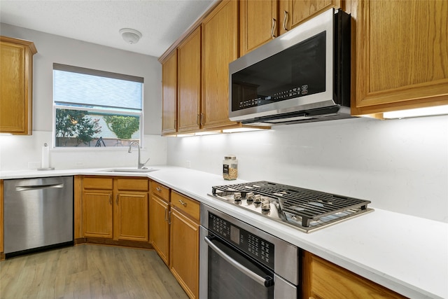 kitchen with sink, stainless steel appliances, and light hardwood / wood-style floors