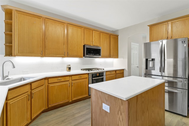 kitchen with sink, stainless steel appliances, a kitchen island, and light hardwood / wood-style floors