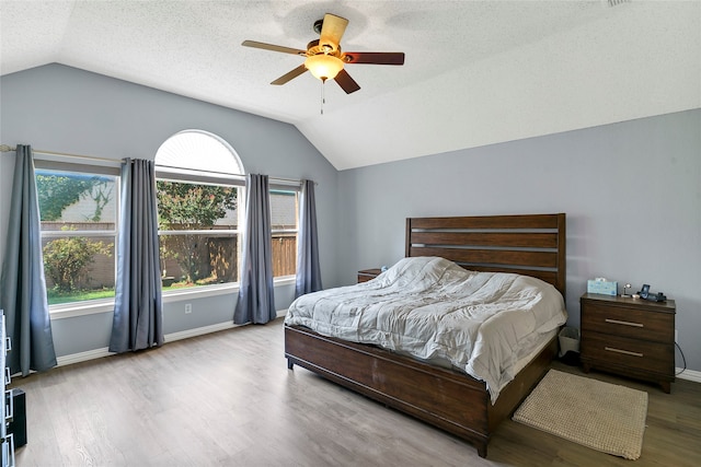 bedroom featuring ceiling fan, light hardwood / wood-style flooring, a textured ceiling, and vaulted ceiling