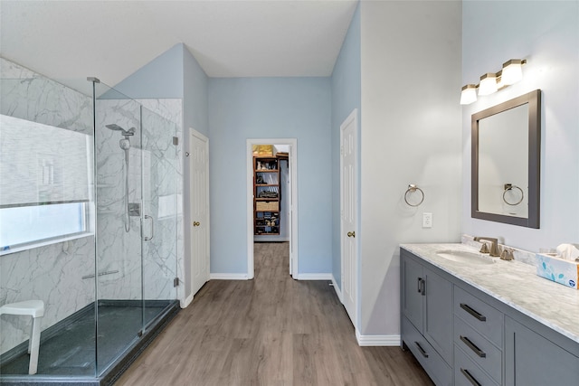 bathroom with hardwood / wood-style floors, a shower with shower door, and vanity