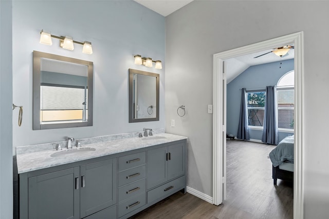 bathroom featuring ceiling fan, vaulted ceiling, wood-type flooring, and dual vanity