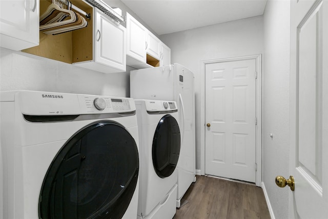 clothes washing area with hardwood / wood-style floors, cabinets, and separate washer and dryer