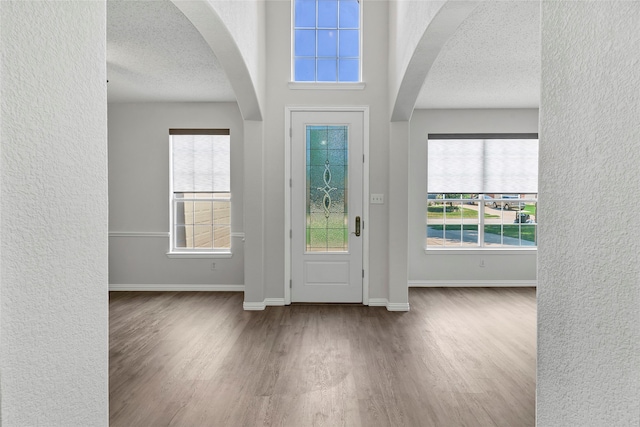 entrance foyer featuring a wealth of natural light, a textured ceiling, and hardwood / wood-style floors