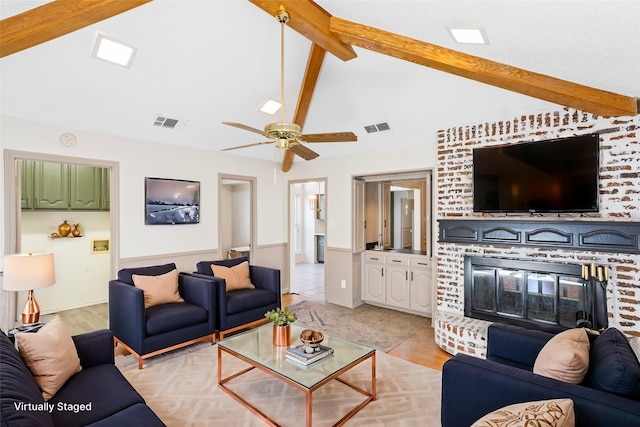 living room with ceiling fan, vaulted ceiling with beams, and a fireplace