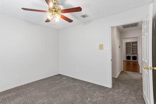 spare room with ceiling fan, a textured ceiling, and dark colored carpet