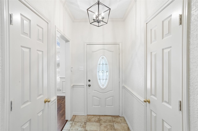 doorway to outside featuring a wealth of natural light, light hardwood / wood-style flooring, a notable chandelier, and ornamental molding