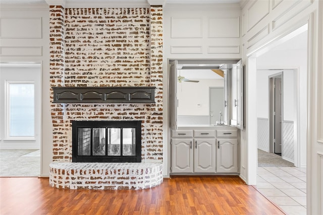 unfurnished living room with decorative columns, light hardwood / wood-style floors, and a brick fireplace